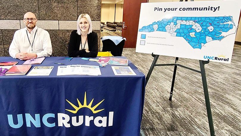 UNC Rural's Associate Director Adam Sotak and Communications Intern Shelby McLamb sharing information at a table at the Minority Health Conference.